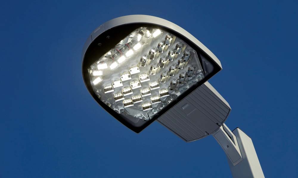 A new, illuminated, LED streetlight against a clear blue sky at dusk