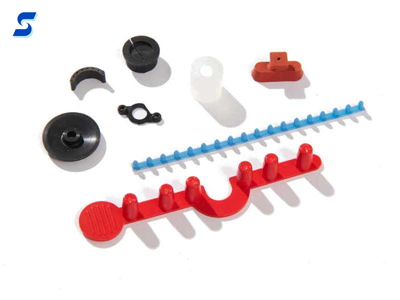 Small red and blue LSR molded parts with risen pegs and other micro gaskets with bumpouts for fit