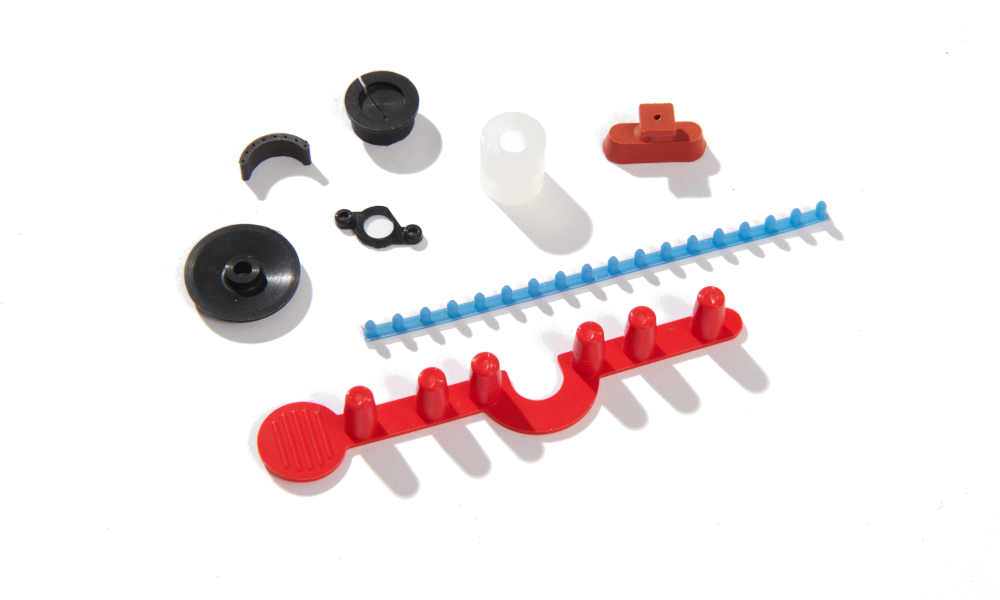 Small red and blue LSR molded parts with risen pegs and other micro gaskets with bumpouts for fit Small red and blue LSR molded parts with risen pegs and other micro gaskets with bumpouts for fit