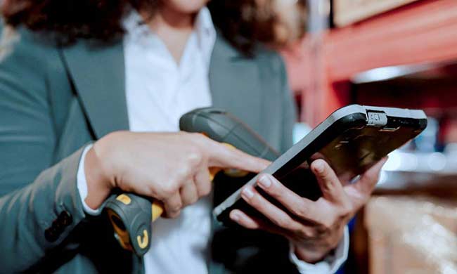 Close up view of staff using a portable data device scanner and tablet in a factory